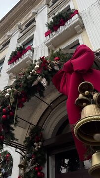 Decorative Christmas street entrance featuring large golden bells adorned with a vibrant red bow and lush greenery, creating a festive holiday atmosphere with seasonal charm
