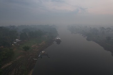 Misty morning view of a river in the Amazon rainforest with canoes