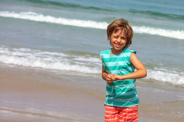 Portrait of happy playful boy on the beach on a sunny summer day