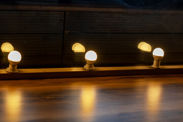 A long row of bright lights are beautifully lit up on a wooden floor