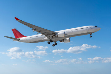 Airplane in the flight, travel background with airplane flying in the blue sky over the clouds. Flying airplane with blank livery