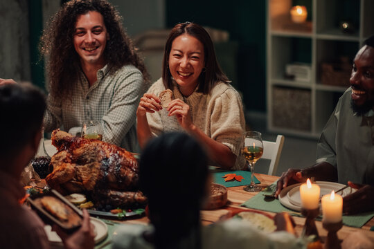 Happy friends enjoying thanksgiving dinner with roasted turkey