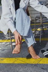 Beautiful women's feet with fresh pedicures in stylish shoes on the street 