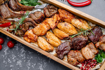 Grilled meat platter with herbs. An overhead shot of assorted grilled meats with herbs, chili peppers, and pomegranate seeds.