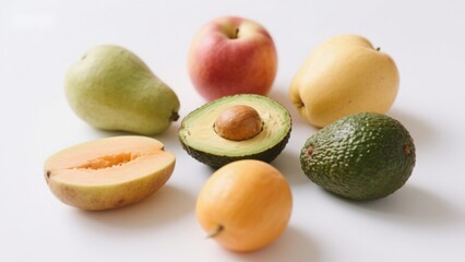 Assorted fresh fruits including avocado, pear, apple, mango, and loquat on a white background