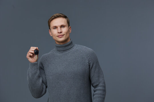 Young caucasian man wearing gray knitted turtleneck holding smart watch smiling confident isolated on gray background digital detox concept health wellness gadget