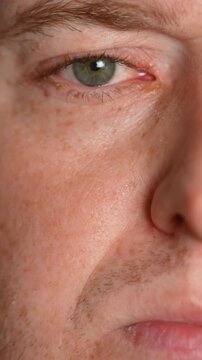 Extreme close up of man's green eye blinking slowly