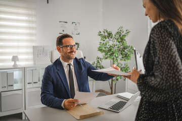 Professional man passing document to woman in office