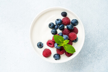 Yogurt with fresh berries in white bowl.
