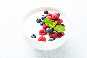 Yogurt with fresh berries in white bowl.