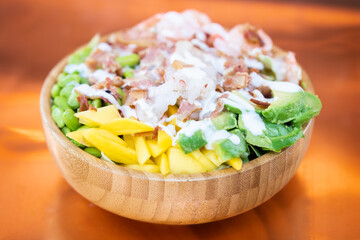 Poke bowl colorata con ingredienti freschi e tropicali in ciotola di legno