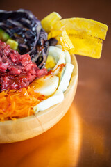 Poke bowl colorata con ingredienti freschi e tropicali in ciotola di legno
