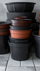 Various sized black and brown plastic plant pots stacked