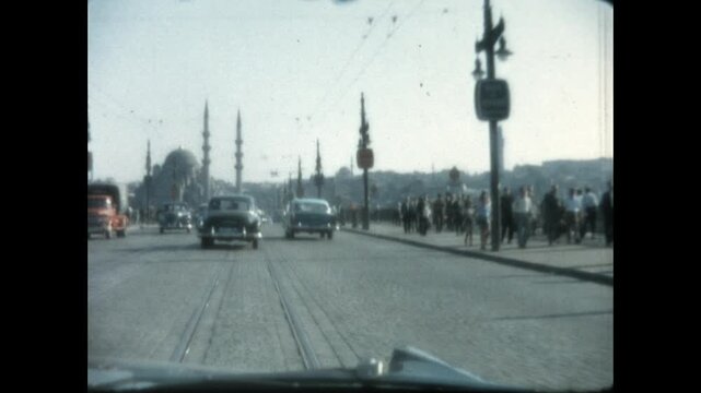 Driving on Galata Bridge 1964 - First person view from a car as it drives south on Galata Bridge, approaching the New Mosque, Yeni Cami, in Istanbul, Turkey in 1964. 