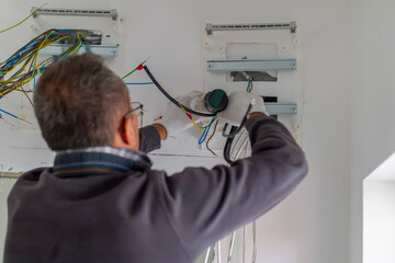 Electrician installs new electrical panel in home. Man electrician performs installation work. Electrical upgrade, improvement of home