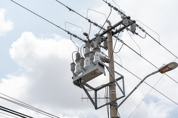 A modern electrical transformer, mounted on a concrete pole and connected to the power distribution...