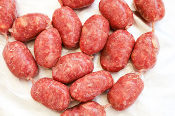 Freshly made sausages displayed on a white surface ready for grilling or cooking