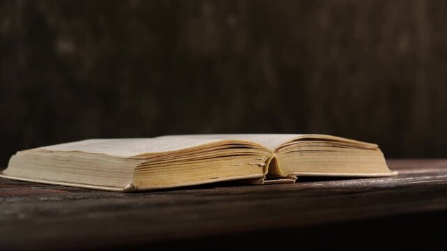 Open old book on wooden rustic table on black background
