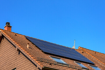 Solarzellen auf Wohnhausdach vor blauem Himmel