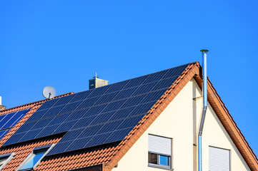 Photovoltaikanlage auf modernem Wohnhaus vor blauem Himmel