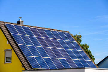 Solarzellen auf Satteldach eines Einfamilienhauses mit maximaler Nutzung der Dachfl&auml;che vor blauem Himmel
