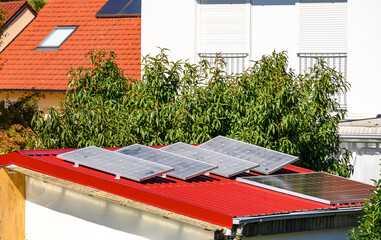 Balkonkraftwerk auf Gartenhaus mit rotem Dach zur umweltfreundlichen Stromerzeugung	