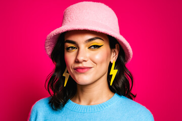 Colorful studio portrait of young woman in pink bucket hat, bold yellow eyeliner and lightning earrings on neon background. generative AI