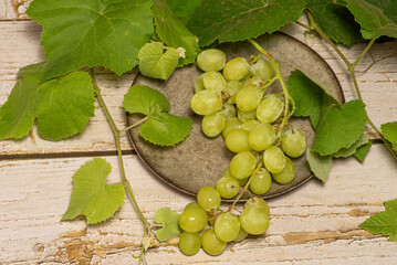 Bunch of grapes, a beautiful bunch of grapes placed on a plate on a rustic wooden surface, selective focus.