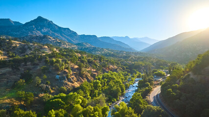 Fototapeta premium Aerial Lush Green River Valley Mountain Foothills and Winding Road at Sunrise