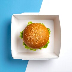 Overhead view of a sesame seed bun burger in a white cardboard container,  placed on a contrasting blue and white background