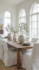 mediterranean coastal dining room full view, oak table, white slipcovered chairs, ceramic vases, arched windows