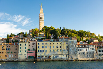 Scenic summer seafront panorama of Rovinj, Croatia, along Adriatic coast featuring pastel colored Venetian-style houses and tall bell tower of St. Euphemia church