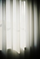 Obraz premium Grey curtains softly filter bright sunlight, creating a warm atmosphere in the room. The light casts gentle shadows, enhancing the peaceful setting Generative AI