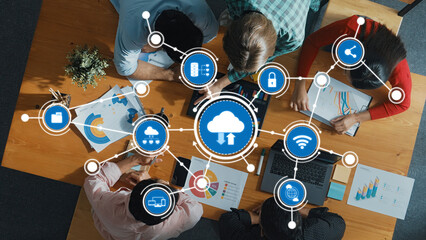 An overhead view of a diverse team of professionals engaged in cloud computing discussions, surrounded by data visualizations and technology icons, symbolizing innovation and strategy. Amity