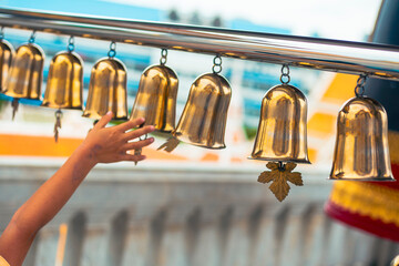 Young hand touching golden bells in a buddhist temple in Bangkok, Thailand