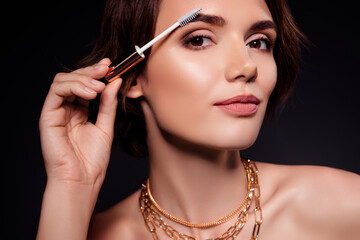 Obraz premium Portrait of charming good mood young girl apply mascara preparing for date isolated on black color background