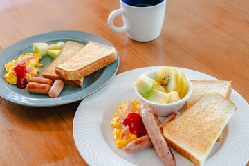 Western breakfast with toast, scrambled eggs, sausages, fruit and coffee
