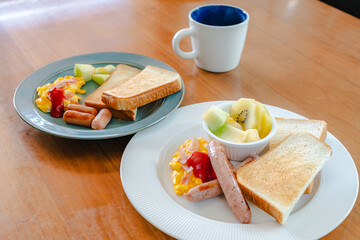Western breakfast with toast, scrambled eggs, sausages, fruit and coffee
