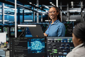 Happy specialist inspecting neural network data center used for machine learning. Portrait of smiling engineer doing maintenance on server hub to optimize it for artificial intelligence workloads.