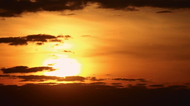 Sun moving across the sky partially hidden by clouds during a golden sunset or sunrise, natural light footage