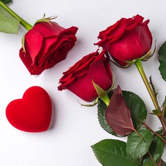 Three vibrant red roses, elegantly arranged on a white surface, with a complementary red velvet heart-shaped box