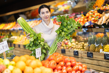 Woman of chooses celery in the vegetable department of a supermarket