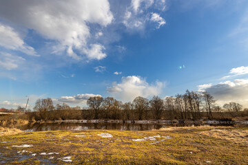 A field with a body of water and trees in the background