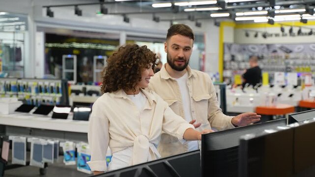 Newlyweds couple choosing tv in electronics store