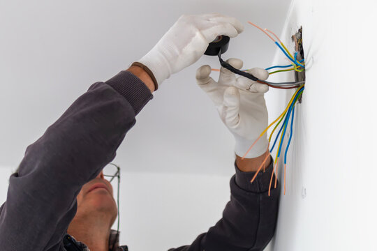 Using electric tape to cover exposed wiring.  Electrician carefully insulates exposed wires in open junction box. Safety during electrical installation work.