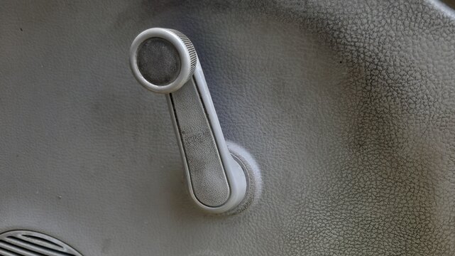 Close up of worn grey window crank handle with subtle scratches and dusty finish.