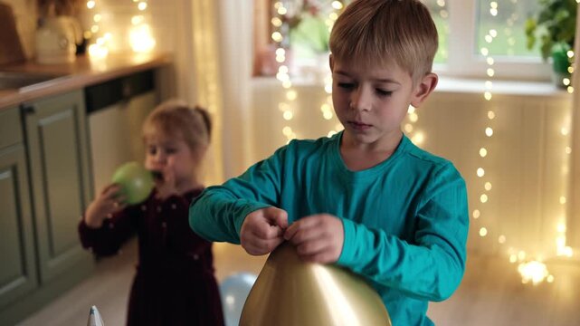 Family Fun Children Joyfully Blowing Up Balloons. Kids inflating balloons, prepare for birthday party. 3,6, 14 years old siblings racing blowing balloon, decorate the room. Bonding time together. Joy