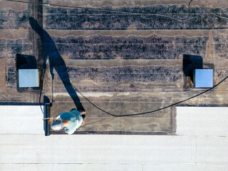 Roofer applying torch to bitumen membrane on torch down roof