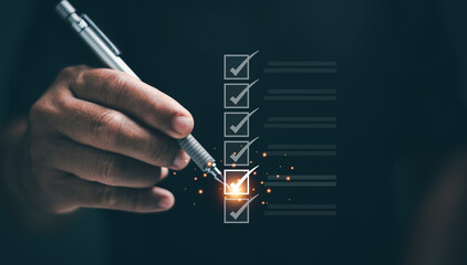 Checklist concept. Businessman holding pen to checking task on glowing digital list. Symbolizing productivity, task management, goal setting, planning and business efficiency in professional workflow.