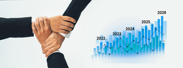 Two business professionals shake hands over a financial growth graph showcasing projections from 2022 to 2026, highlighting collaboration and success in a modern office. Trope